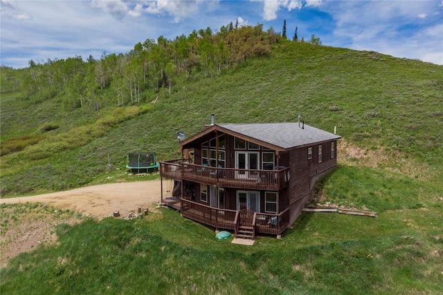 27100 Neptune Pl, Clark, CO 80428 - rear view of property featuring a trampoline, a wooden deck, a lawn, and driveway