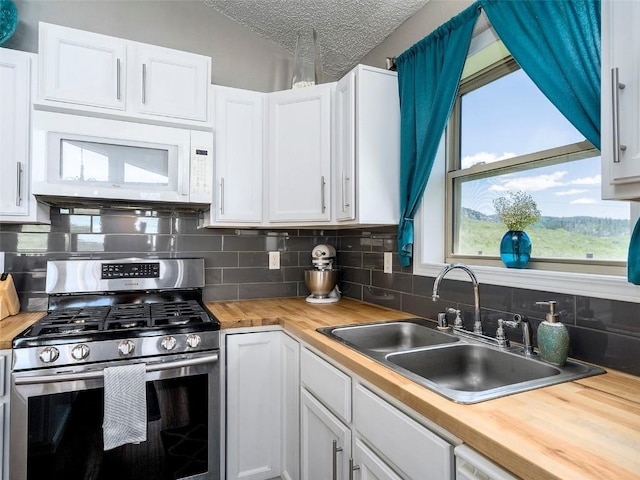 27100 Neptune Pl, Clark, CO 80428 - kitchen with stainless steel gas range, wooden counters, white microwave, tasteful backsplash, and white cabinets