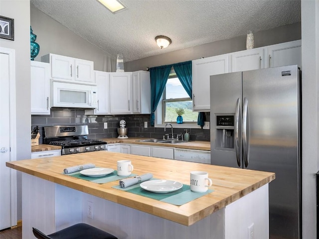 27100 Neptune Pl, Clark, CO 80428 - kitchen with wooden counters, appliances with stainless steel finishes, white cabinetry, decorative backsplash, and a kitchen bar