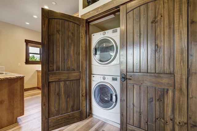 washroom with light wood-style flooring, baseboards, recessed lighting, stacked washer / drying machine, and laundry area