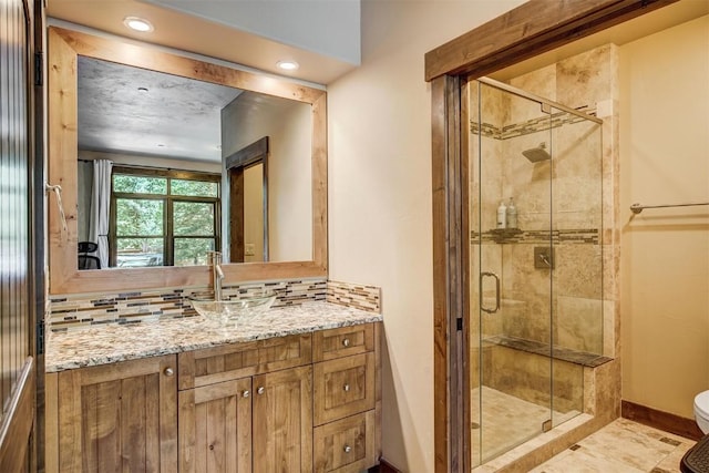 bathroom featuring a shower stall, toilet, vanity, baseboards, and tasteful backsplash