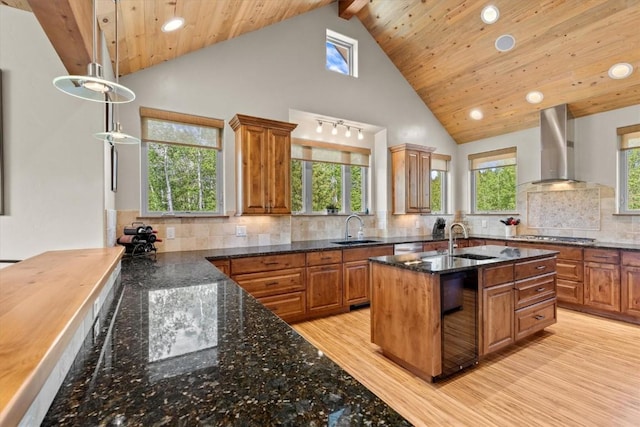 kitchen featuring brown cabinetry, a sink, wall chimney exhaust hood, and recessed lighting