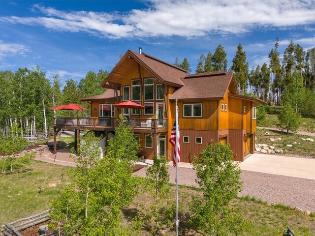 back of house featuring a wooden deck and driveway