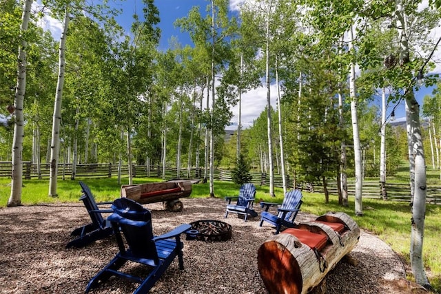 surrounding community with a fire pit and fence