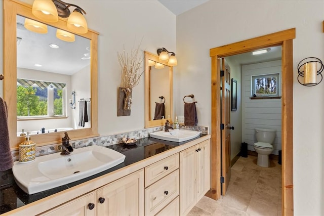 full bathroom with double vanity, a sink, and toilet