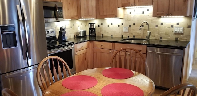 kitchen featuring a sink, appliances with stainless steel finishes, tasteful backsplash, and dark stone countertops