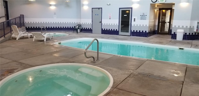 pool with a patio, fence, and an indoor hot tub