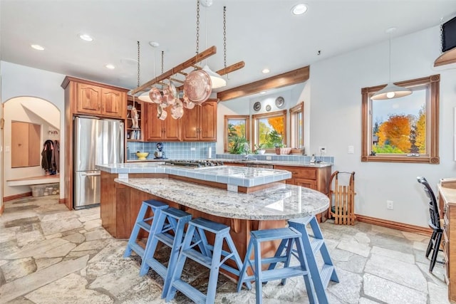 kitchen featuring hanging light fixtures, tasteful backsplash, a kitchen island, a kitchen bar, and stainless steel appliances