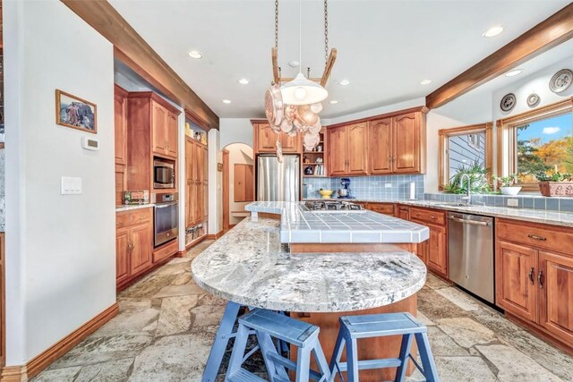 kitchen with a kitchen island, backsplash, appliances with stainless steel finishes, and a breakfast bar area