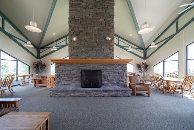 living room with ceiling fan, a stone fireplace, beamed ceiling, high vaulted ceiling, and carpet floors