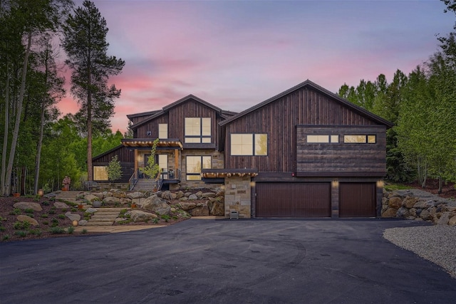 chalet / cabin with aphalt driveway and stone siding
