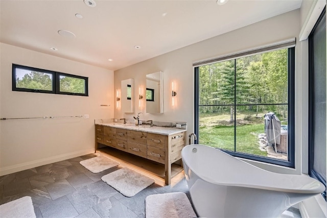 full bathroom featuring recessed lighting, a freestanding tub, baseboards, and vanity