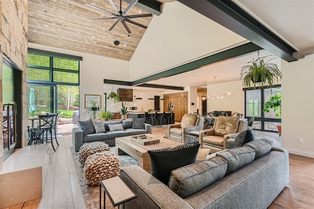 living room featuring beamed ceiling, high vaulted ceiling, wood finished floors, and ceiling fan with notable chandelier