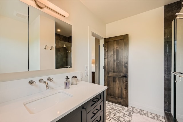 full bath with vanity, baseboards, and a tile shower