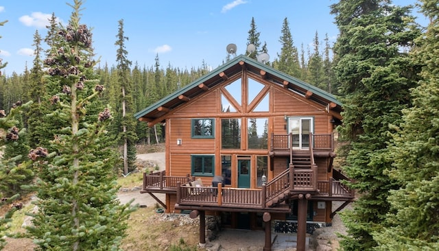 back of house featuring a wooded view and a deck