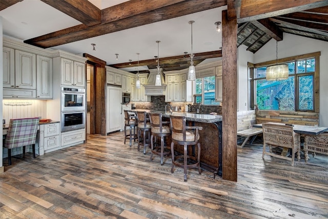 19 Peak 8 Ct, Breckenridge, CO 80424 - kitchen with stainless steel double oven, wood finished floors, beam ceiling, a kitchen bar, and tasteful backsplash
