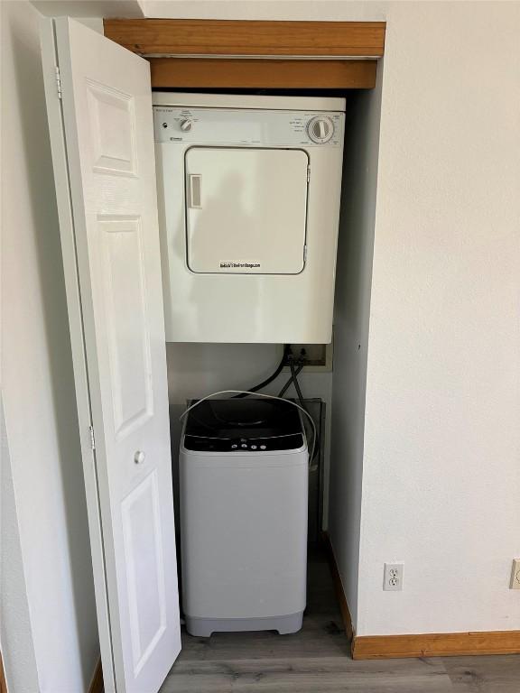 1550 Red Hawk Ct, Steamboat Springs, CO 80487 - clothes washing area with baseboards, wood finished floors, stacked washing maching and dryer, and laundry area