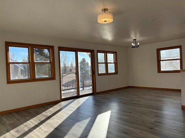 1550 Red Hawk Ct, Steamboat Springs, CO 80487 - spare room featuring dark wood-type flooring, a wealth of natural light, baseboards, and a notable chandelier