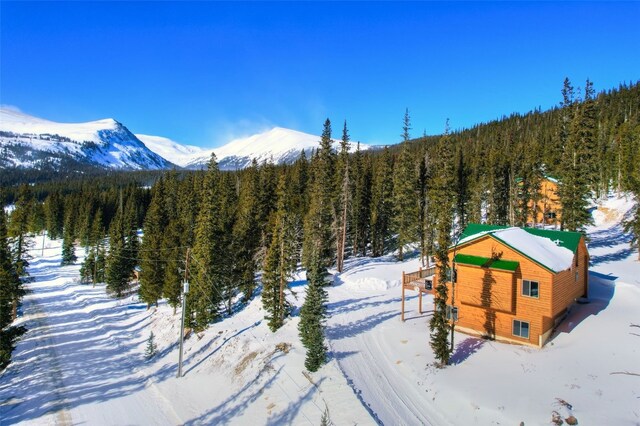 snowy aerial view with a wooded view and a mountain view