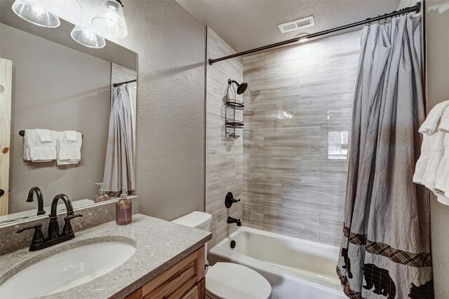 bathroom with shower / tub combo with curtain, toilet, vanity, and a textured wall