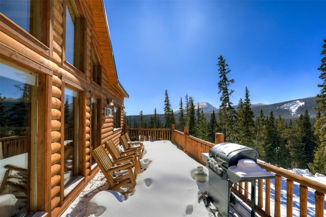 snow covered patio featuring a mountain view, a wooded view, a balcony, and grilling area