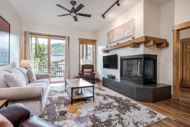 1463 Flattop Cir Unit 302, Steamboat Springs, CO 80487 - living area featuring track lighting, a glass covered fireplace, wood finished floors, and ceiling fan