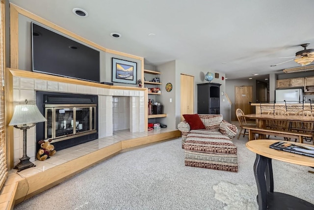 carpeted living room featuring a tiled fireplace and a ceiling fan