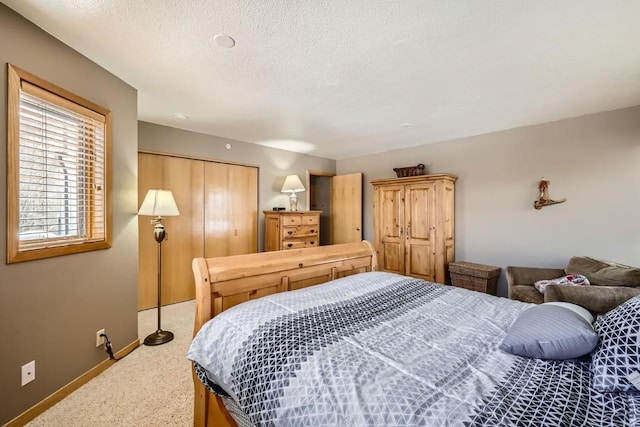 bedroom with light colored carpet, baseboards, a textured ceiling, and a closet
