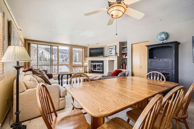 dining room with a glass covered fireplace, baseboards, and ceiling fan