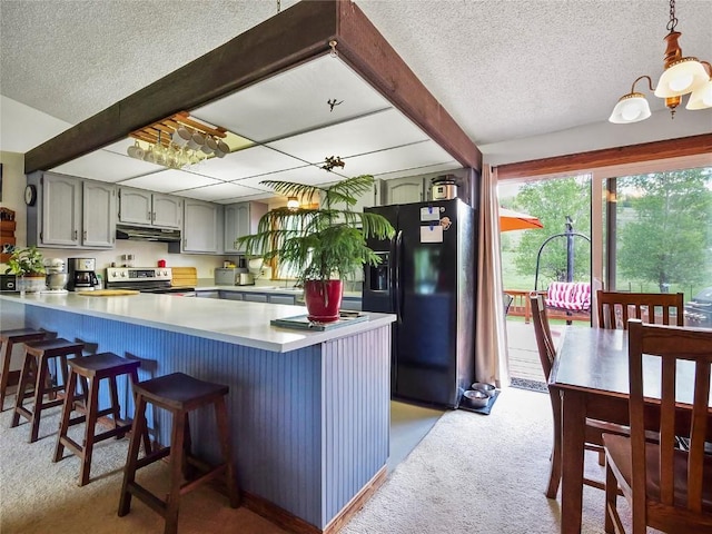 1346 Rainbow Dr, Silverthorne, CO 80498 - kitchen with black fridge with ice dispenser, light carpet, under cabinet range hood, a peninsula, and a textured ceiling