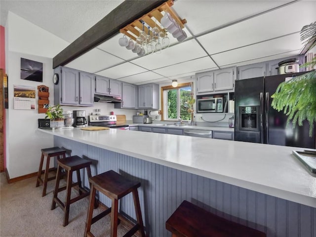 1346 Rainbow Dr, Silverthorne, CO 80498 - kitchen with stainless steel appliances, under cabinet range hood, a peninsula, light countertops, and a kitchen breakfast bar
