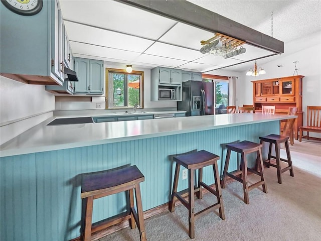1346 Rainbow Dr, Silverthorne, CO 80498 - kitchen featuring black refrigerator with ice dispenser, stainless steel microwave, a peninsula, light countertops, and light colored carpet