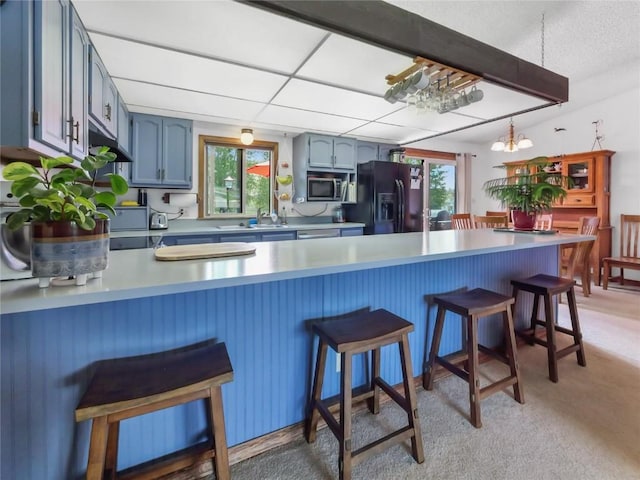 1346 Rainbow Dr, Silverthorne, CO 80498 - kitchen featuring black fridge with ice dispenser, stainless steel microwave, a peninsula, blue cabinets, and light countertops