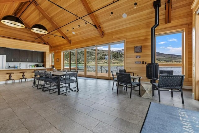 11 Glazer Trl, Silverthorne, CO 80498 - tiled dining room featuring wood ceiling, wood walls, beamed ceiling, and a wood stove
