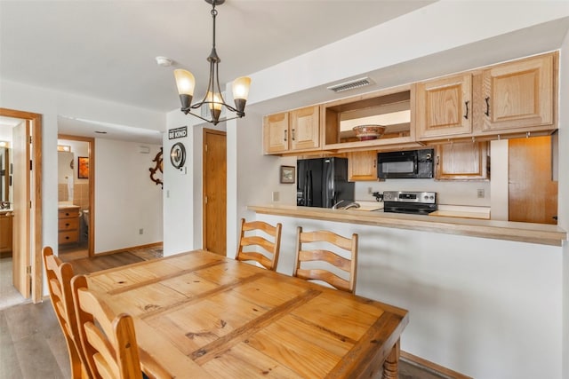 dining space featuring wood finished floors, visible vents, baseboards, and an inviting chandelier