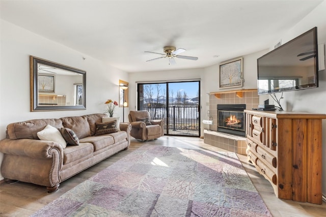 living area featuring light wood-style flooring, a fireplace, and ceiling fan