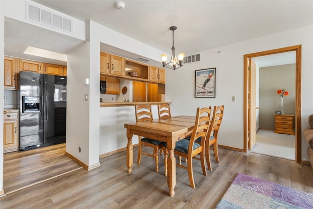dining room featuring baseboards, a notable chandelier, light wood finished floors, and visible vents