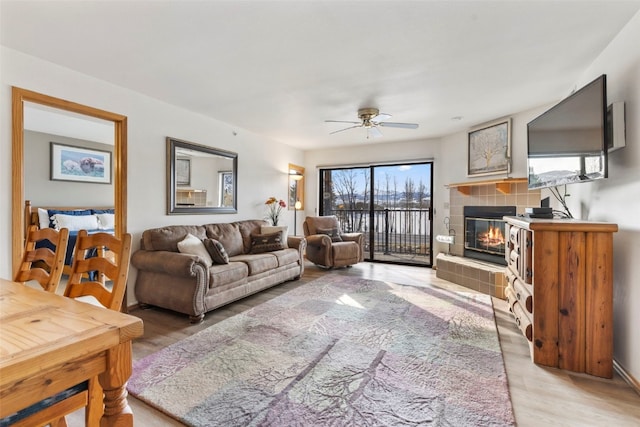 living area with light wood finished floors, a fireplace, and ceiling fan
