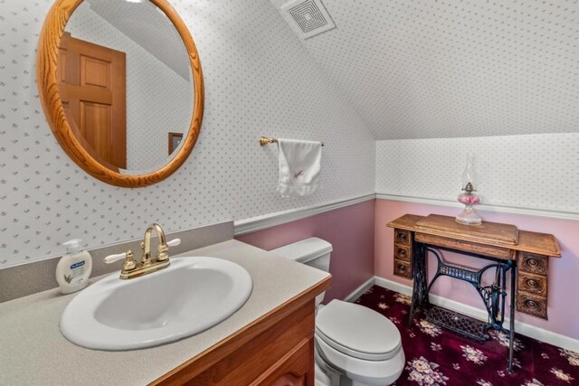 34995 Country Green Rd, Steamboat Springs, CO 80487 - half bathroom featuring toilet, visible vents, lofted ceiling, wallpapered walls, and vanity