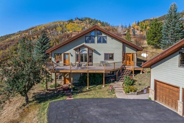 34995 Country Green Rd, Steamboat Springs, CO 80487 - back of property featuring a deck with mountain view, a wooded view, a garage, stairs, and aphalt driveway