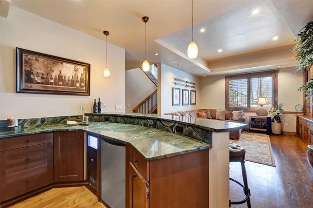 2542 Ski Trail Ln, Steamboat Springs, CO 80487 - interior space with dark stone counters, light wood-style flooring, a sink, open floor plan, and a kitchen bar