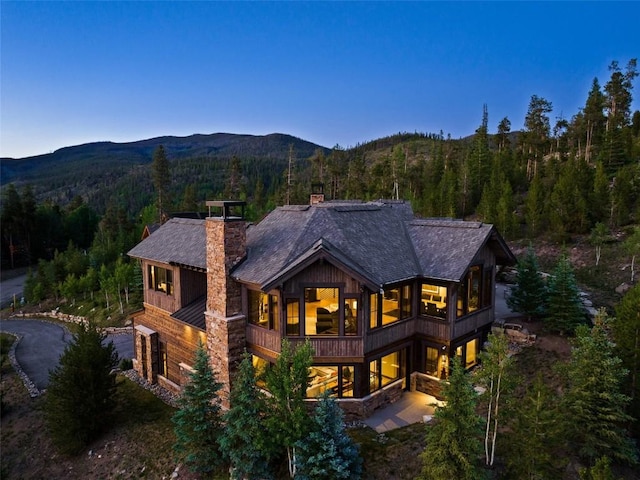 455 Highfield Trl, Breckenridge, CO 80424 - back of house with a chimney, a forest view, a mountain view, roof with shingles, and a balcony