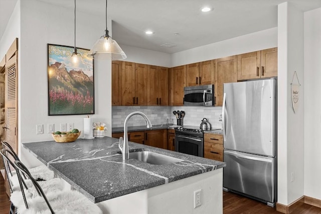 kitchen featuring brown cabinetry, a sink, a peninsula, and stainless steel appliances