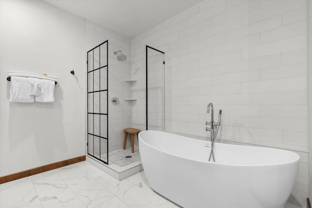 full bath featuring a freestanding tub, a shower stall, baseboards, and marble finish floor