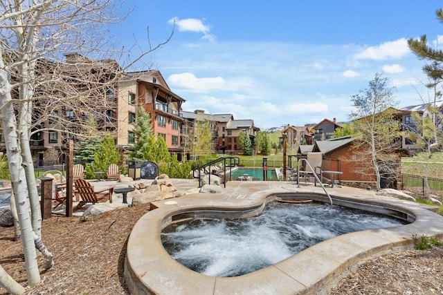 community pool with a patio, a community hot tub, and fence
