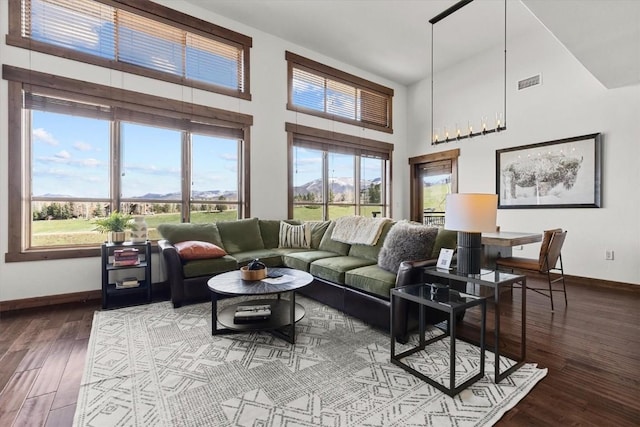 living room with baseboards, wood finished floors, a towering ceiling, visible vents, and a mountain view