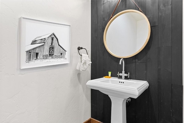 bathroom featuring wood walls and a sink
