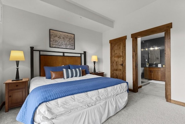 bedroom with baseboards, light colored carpet, and ensuite bath