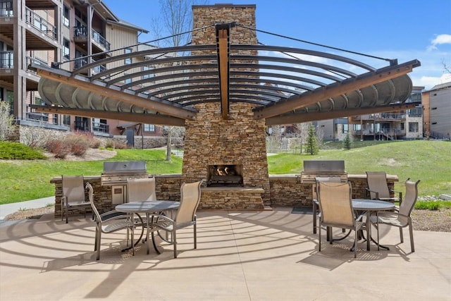 view of patio featuring an outdoor stone fireplace, exterior kitchen, and grilling area