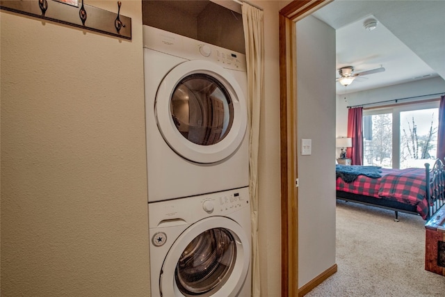 clothes washing area featuring a ceiling fan, stacked washer and clothes dryer, and carpet